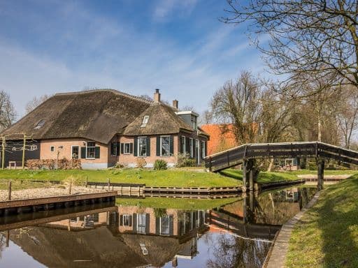 Old farm with reflection in the water in Giethoorn, Netherlands